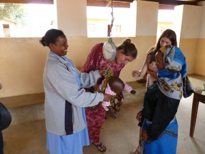 Helena Michael weighing a baby in Mondo, Tanzania, with assistance from Peace Corps Volunteer Heather Teixeira.