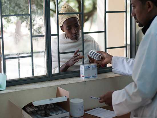 A SIAPS supported pharmacist hands medicine to a woman in Ethiopia.